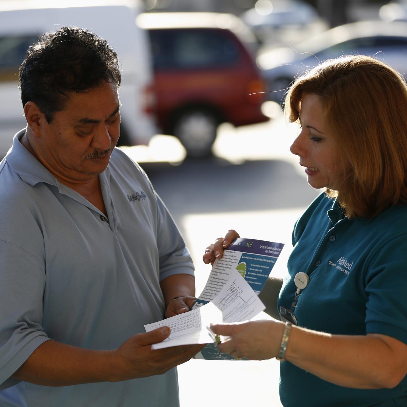 A patient care coordinator at AltaMed, speaks to a man during a community outreach on Obamacare.