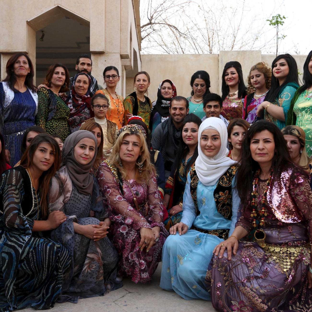 Kurdish women wearing traditional clothes pose for a picture.