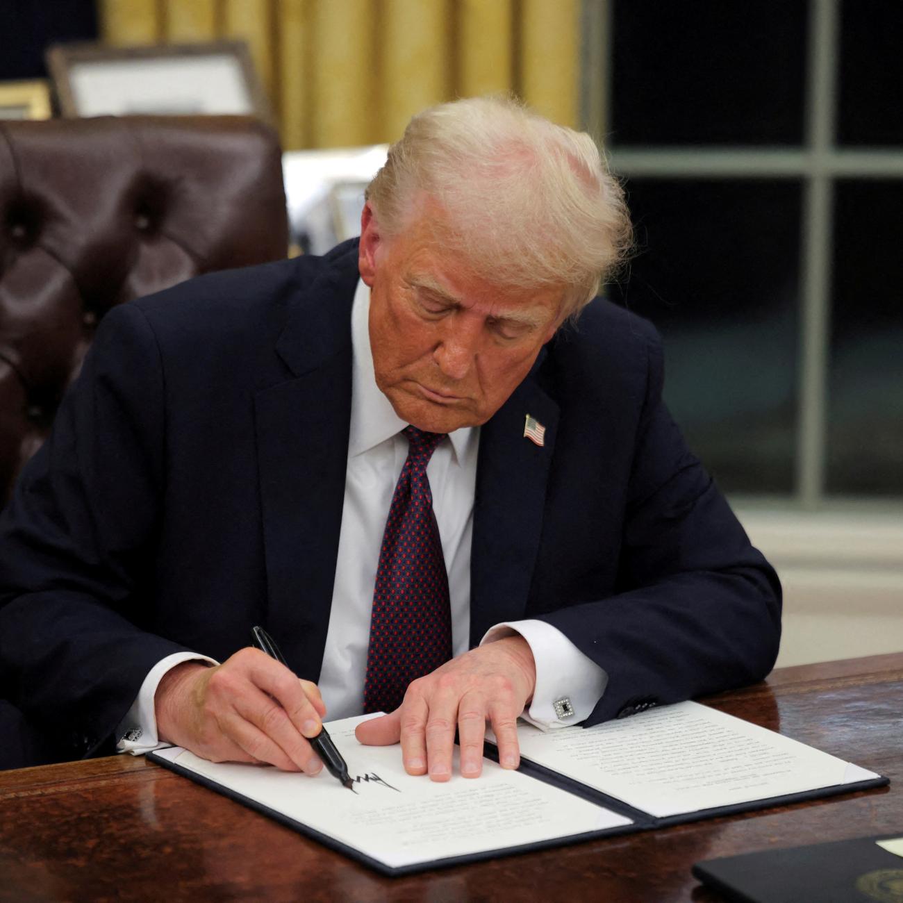 U.S. President Donald Trump signs documents as he issues executive orders and pardons in the Oval Office at the White House, on Inauguration Day, in Washington, DC, on January 20, 2025. 