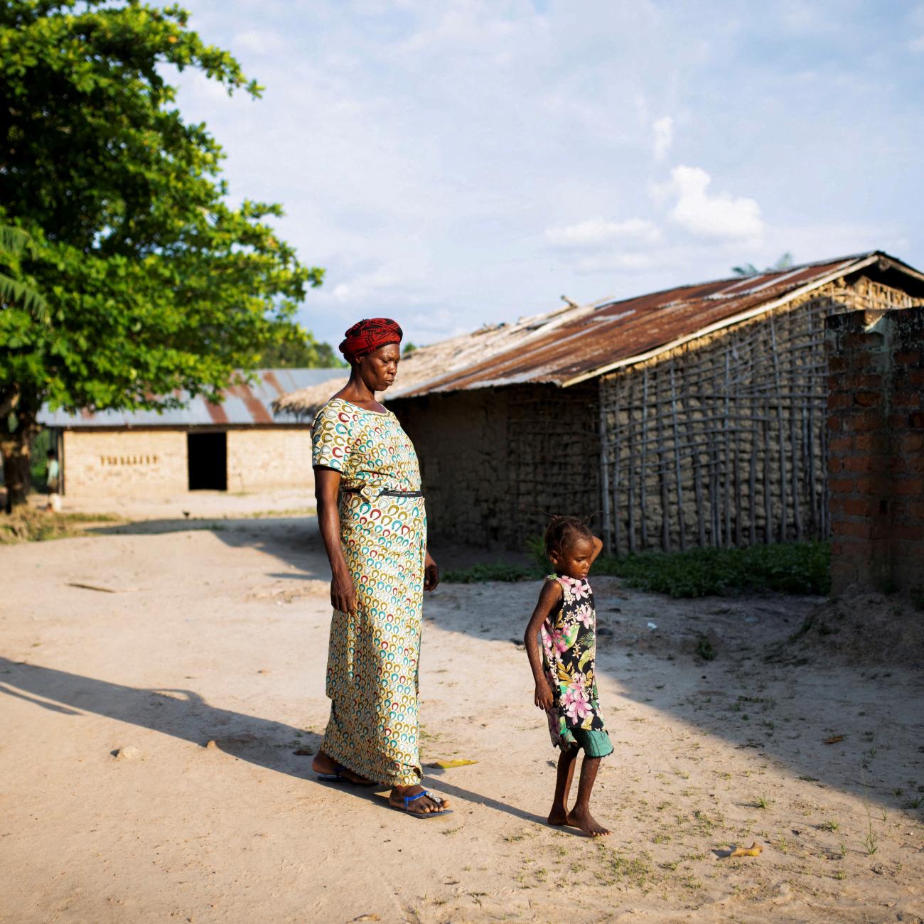 A woman walks her granddaughter to the restroom after having samples collected, at the Yalolia health center, in Yakusu, Tshopo, Democratic Republic of Congo, on October 3, 2022.