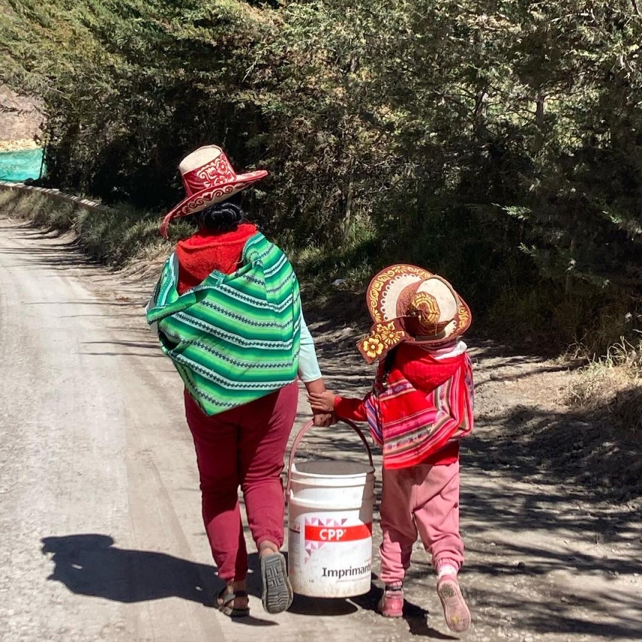 A mother and her daughter carry grain to their home in rural Cusco, Peru, on July 21, 2022