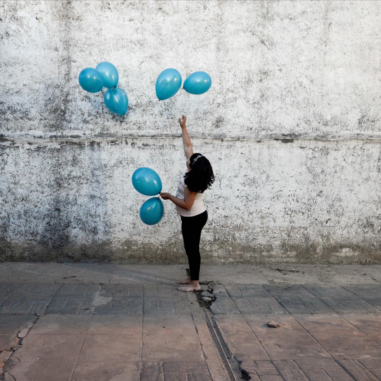 Michell, granddaughter of Rosalia Reyes who was sentenced to eight years in prison after her baby died during a home childbirth, plays with balloons during the welcome party for Rosalia after she was transferred home where she will serve the rest of her time under house arrest