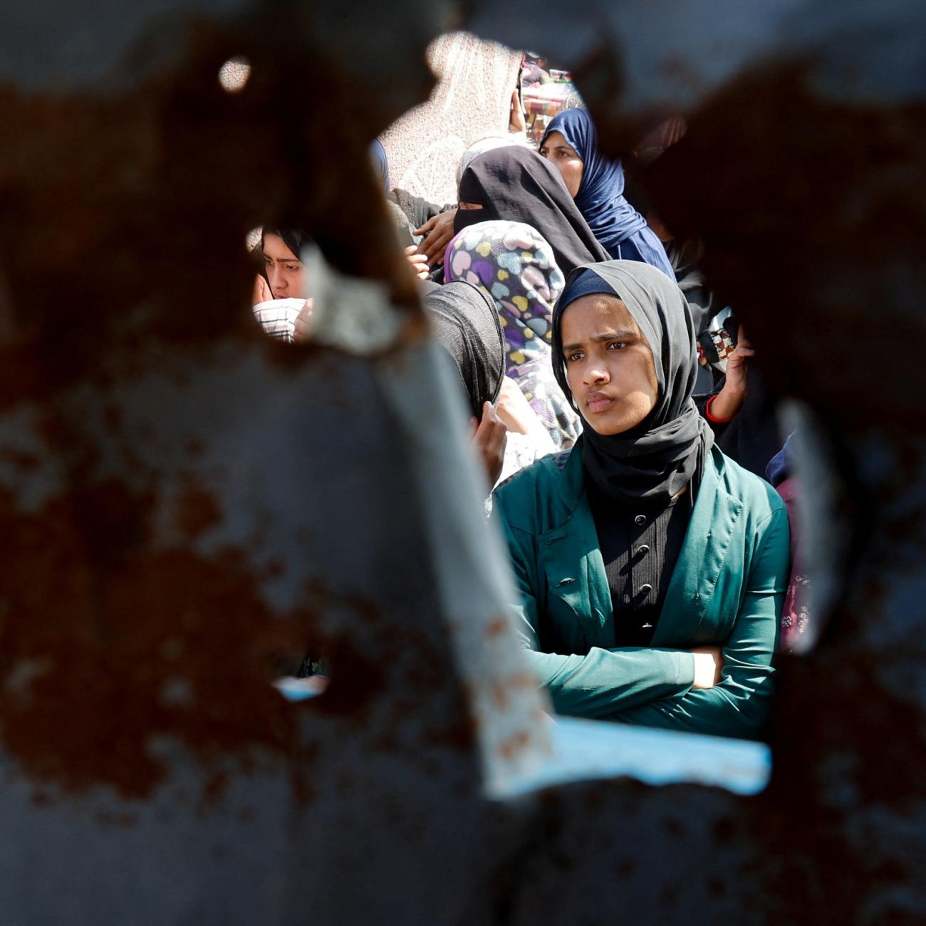 A Palestinian woman looks on as she and others gather to receive bread from a bakery, in Khan Younis, Gaza Strip, on March 9, 2025.