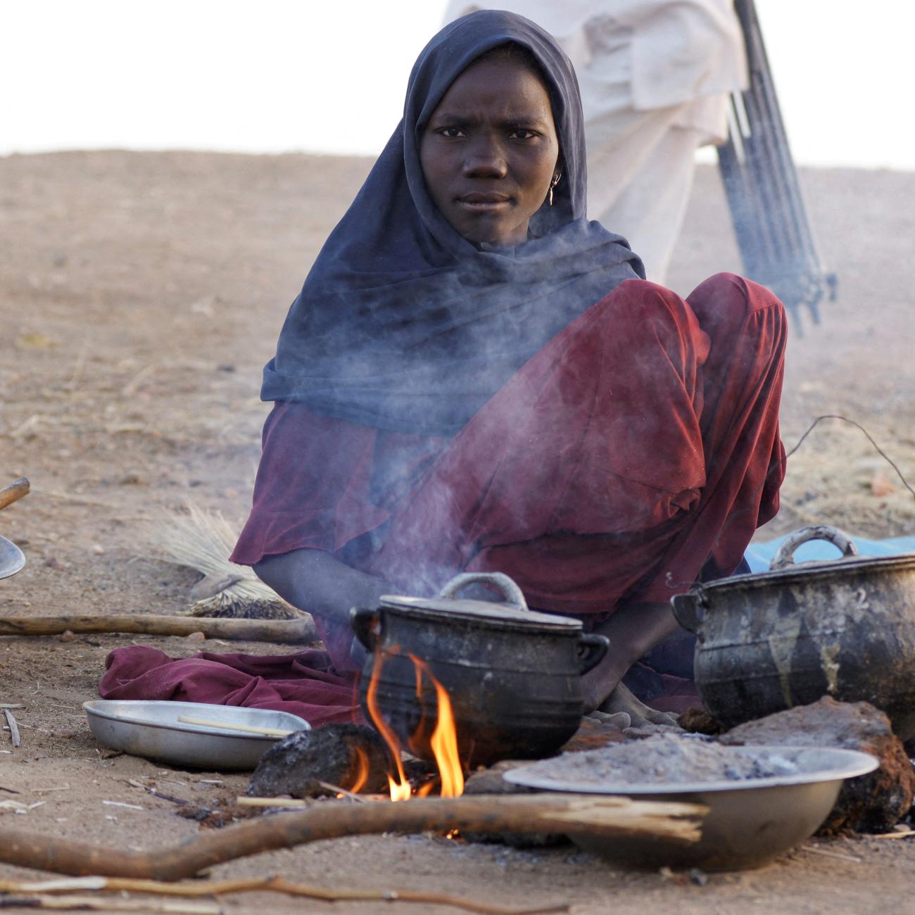 A displaced woman prepares food, following Rapid Support Forces attacks on Zamzam displacement camp, as she shelters in the town of Tawila, in North Darfur, Sudan, on April 16, 2025.