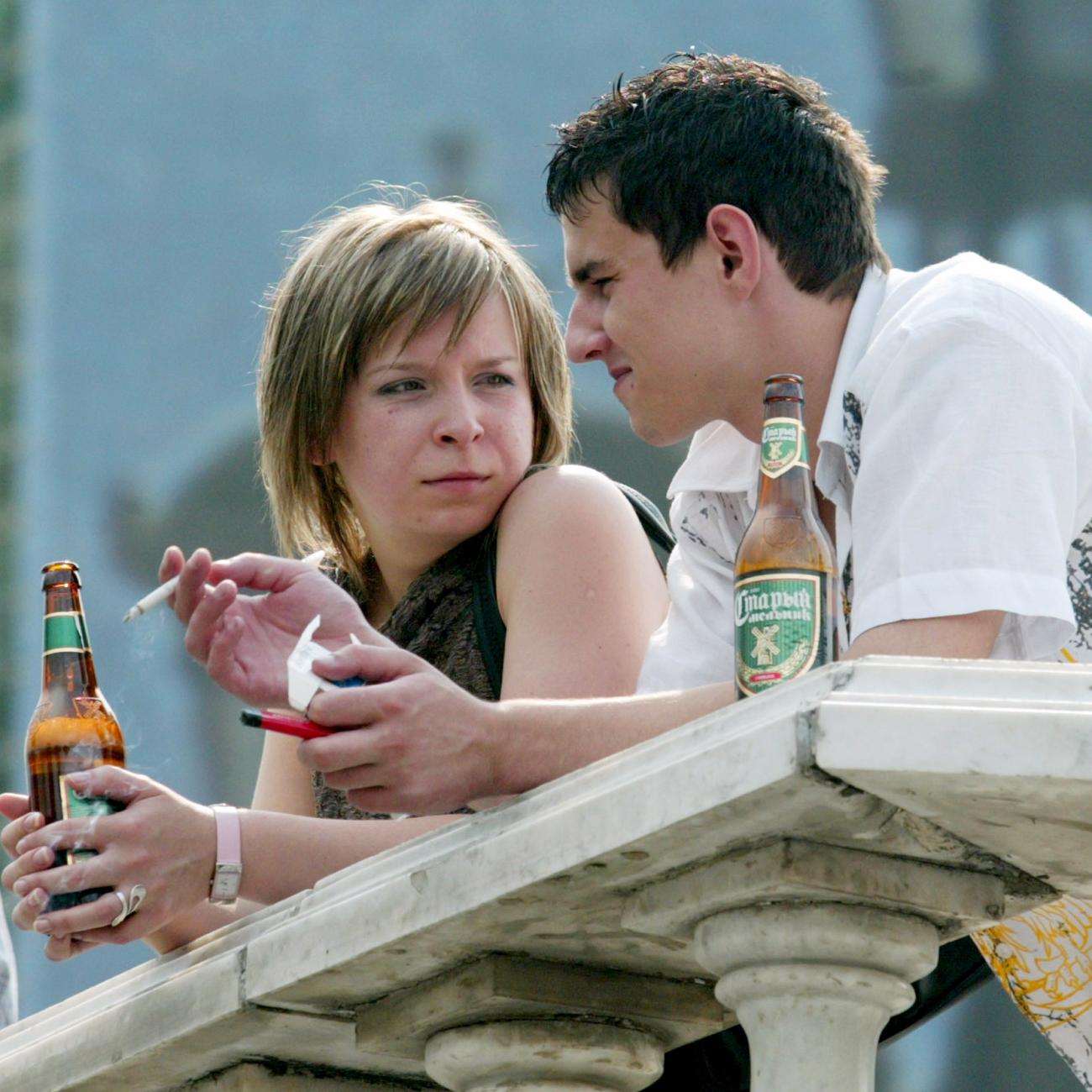 A young couple chat as they drink beer and smoke cigarettes, in Moscow, Russia, on August 8, 2004.