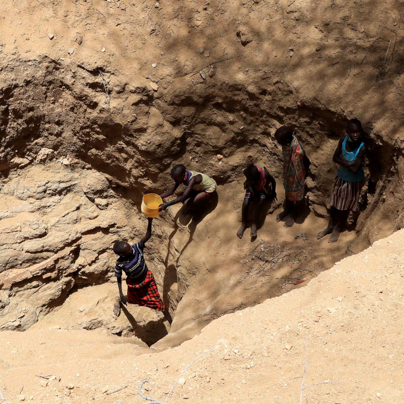 Members of the Turkana pastoralist community affected by the worsening drought due to failed rain seasons, collect water from an open well dug on a dry riverbed, Turkana, Kenya, on September 27, 2022.