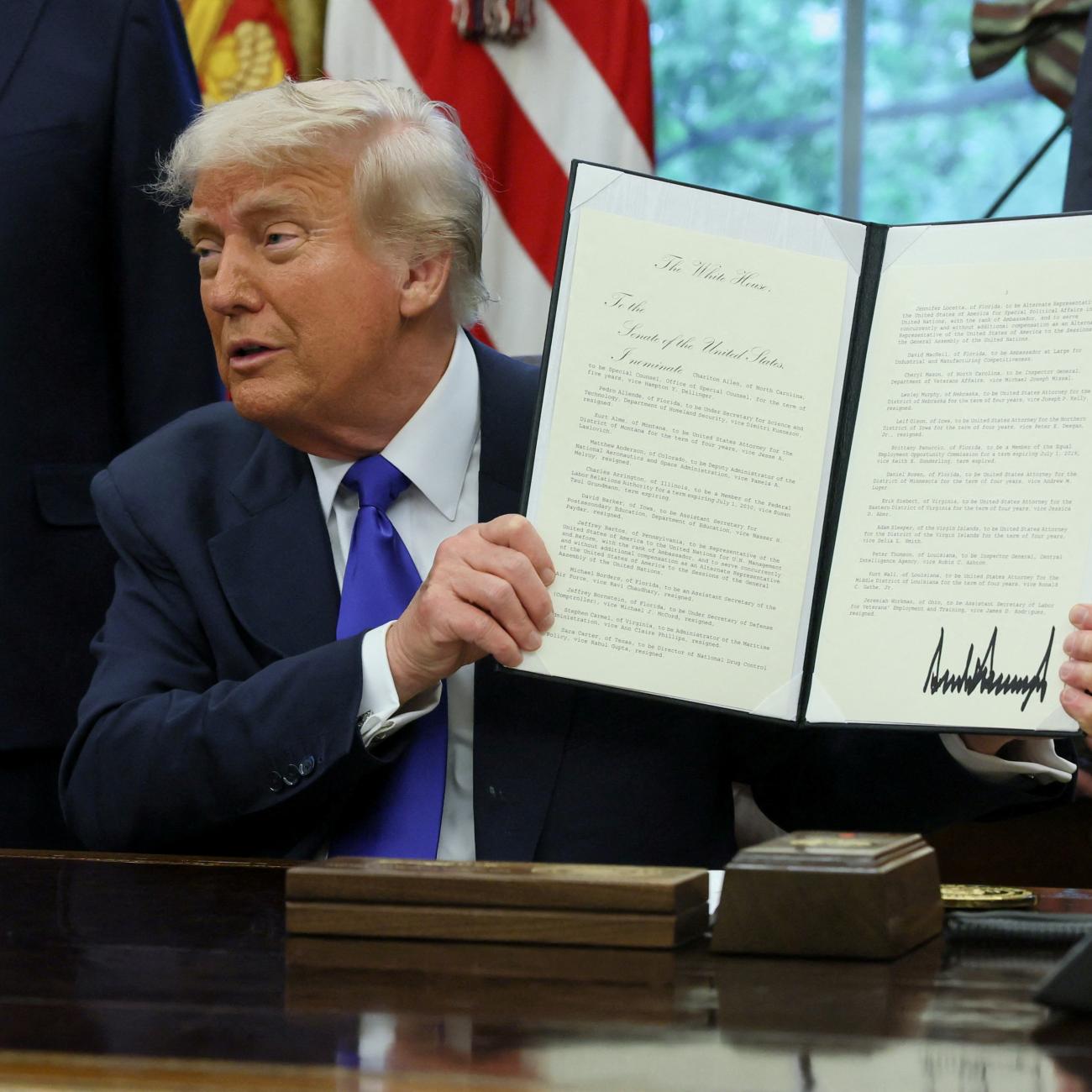 U.S. President Donald Trump shows a signed document as he signs executive orders and proclamations in the Oval Office at the White House, in Washington, DC, on May 5, 2025. 