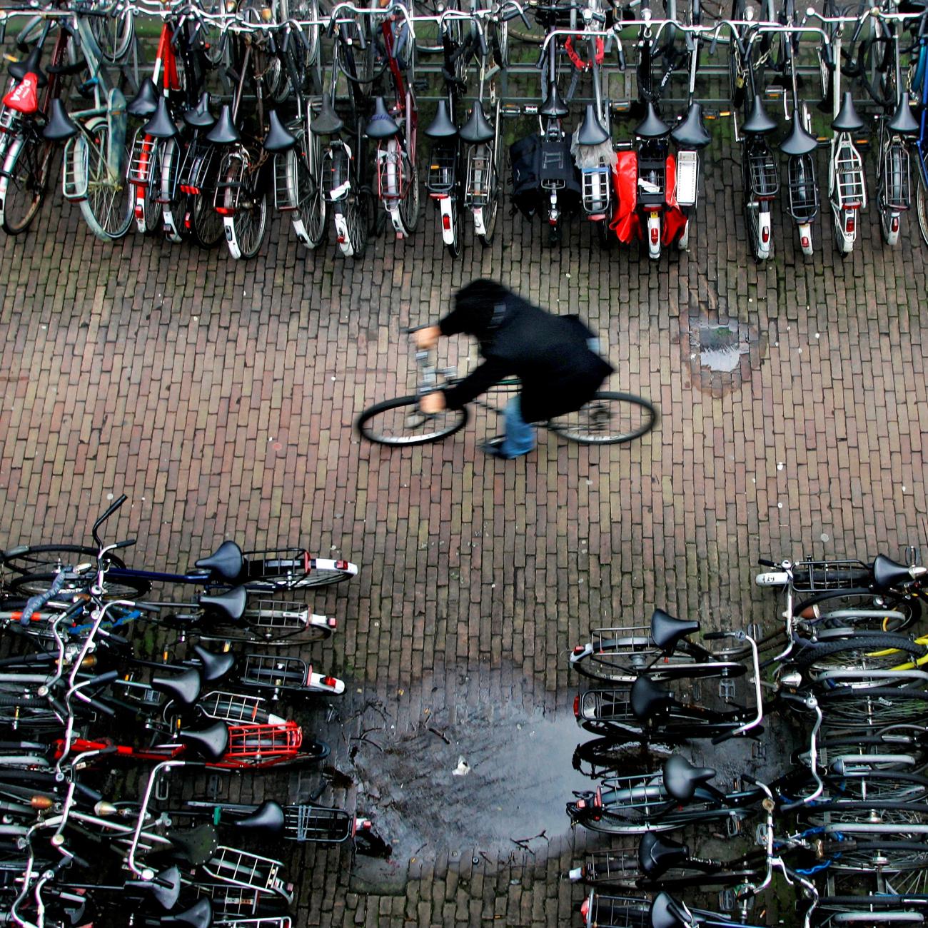 A man rides his bike in a bicycle shed near Central Station Amsterdam January 17, 2007. There are more bicycles than people in the Netherlands, where each resident clocks up an average of 917 kilometers (573 miles) a year on two wheels.