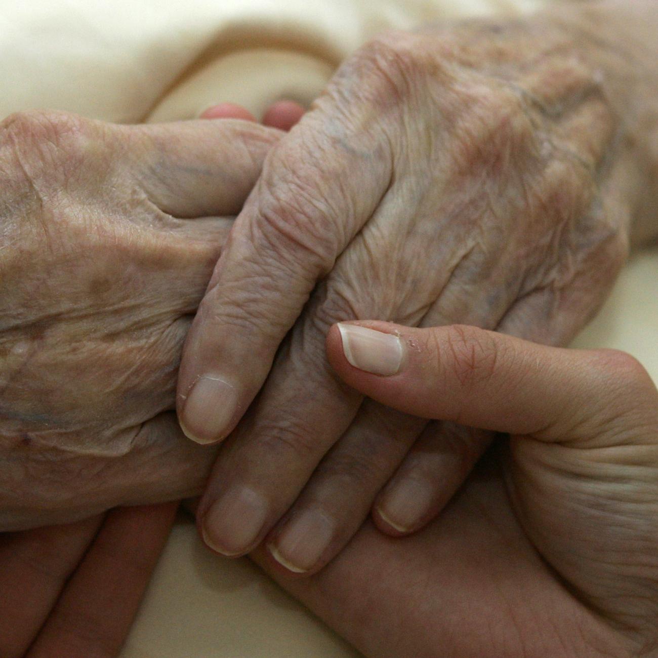 A caregiver holds the hands of an elderly woman, in Planegg, Germany, on June 19, 2007.