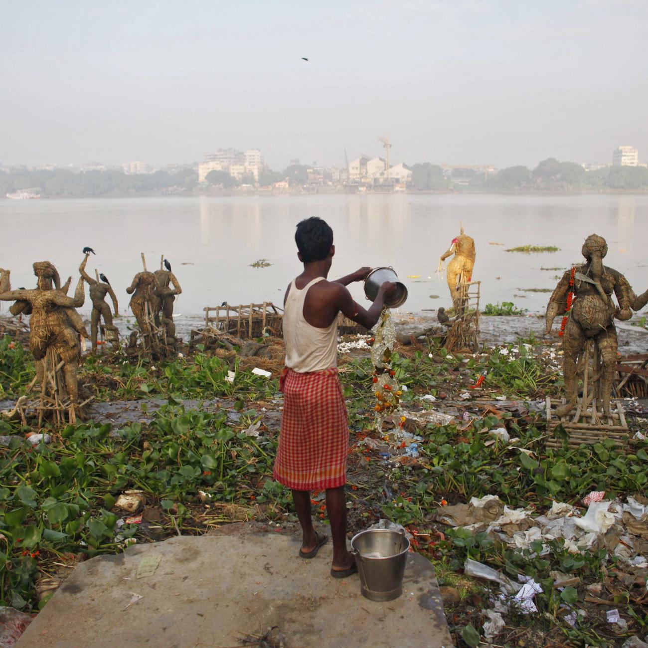 A man pours water on the polluted banks of river Ganges, in Kolkata, India, on October 20, 2010. 