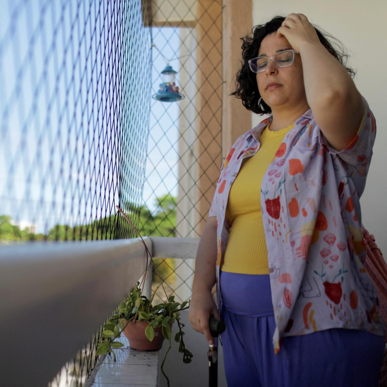 Leticia de Souza Soares, who suffers from pain and health problems caused by long COVID-19, stands on the balcony of her home, in Salvador, Brazil, on December 8, 2023. 