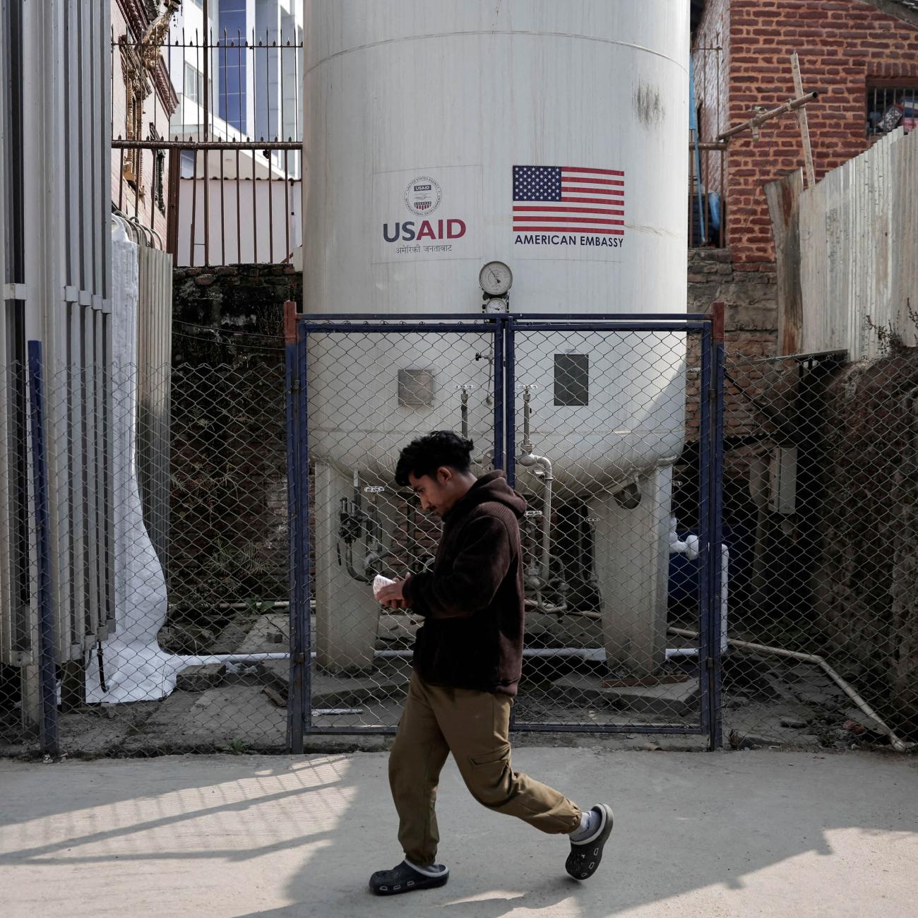 A man walks past the liquid oxygen storage tank installed at Bir Hospital by the United States Agency for International Development, in Kathmandu, Nepal, on February 9, 2025. 