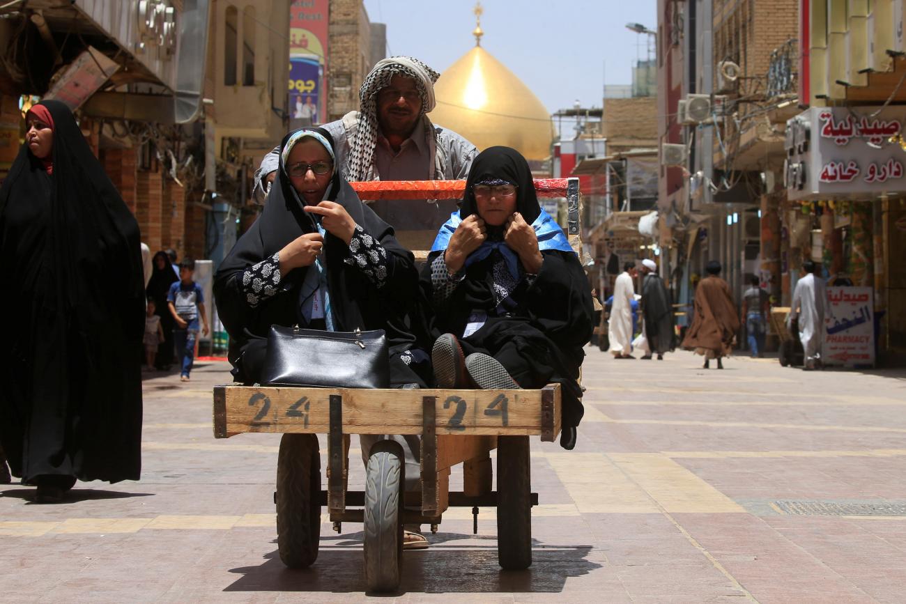 A man pushes a cart to transport women in Najaf, Iraq.