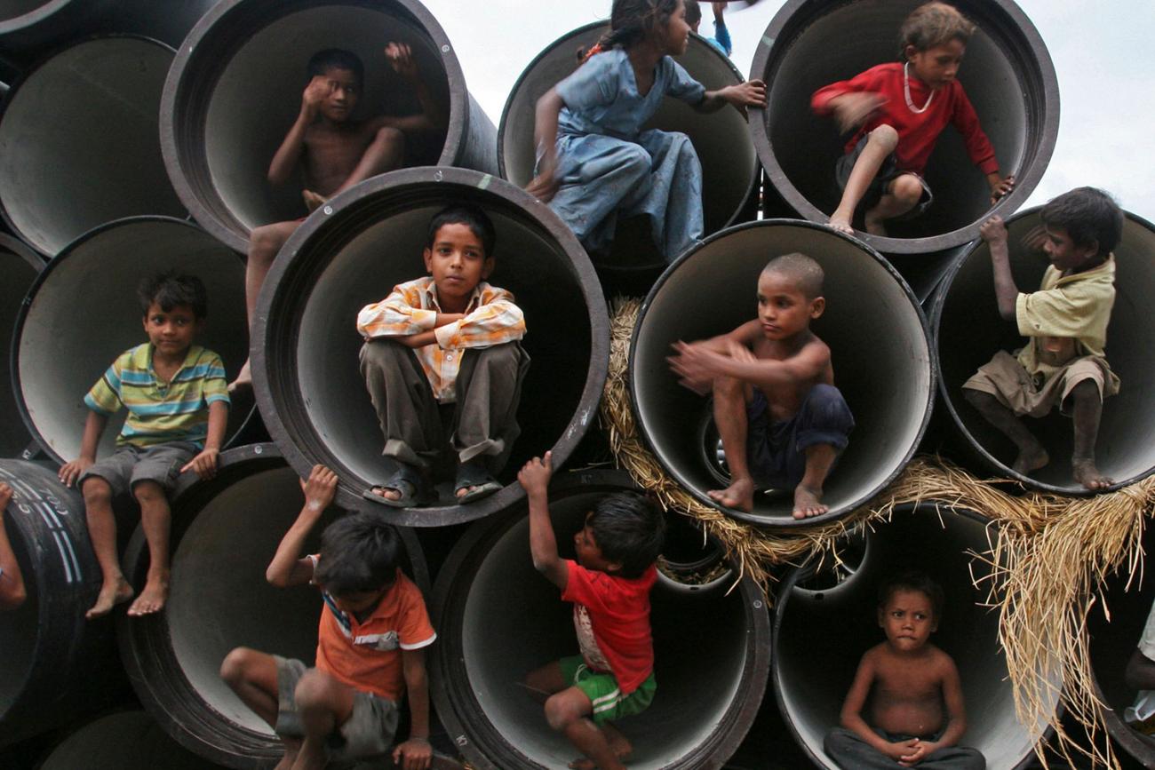 Children play in water pipes at a construction site on the banks of the Yamuna River on July 26, 2010in the northern Indian city of Allahabad. Picture shows several rows of large, concrete sewer pipes stacked on top of each other with their fat openings facing the camera. Each is large enough to fit one child huddled at the opening. About ten children can be seen climbing about on the feature. REUTERS/Jitendra Prakash