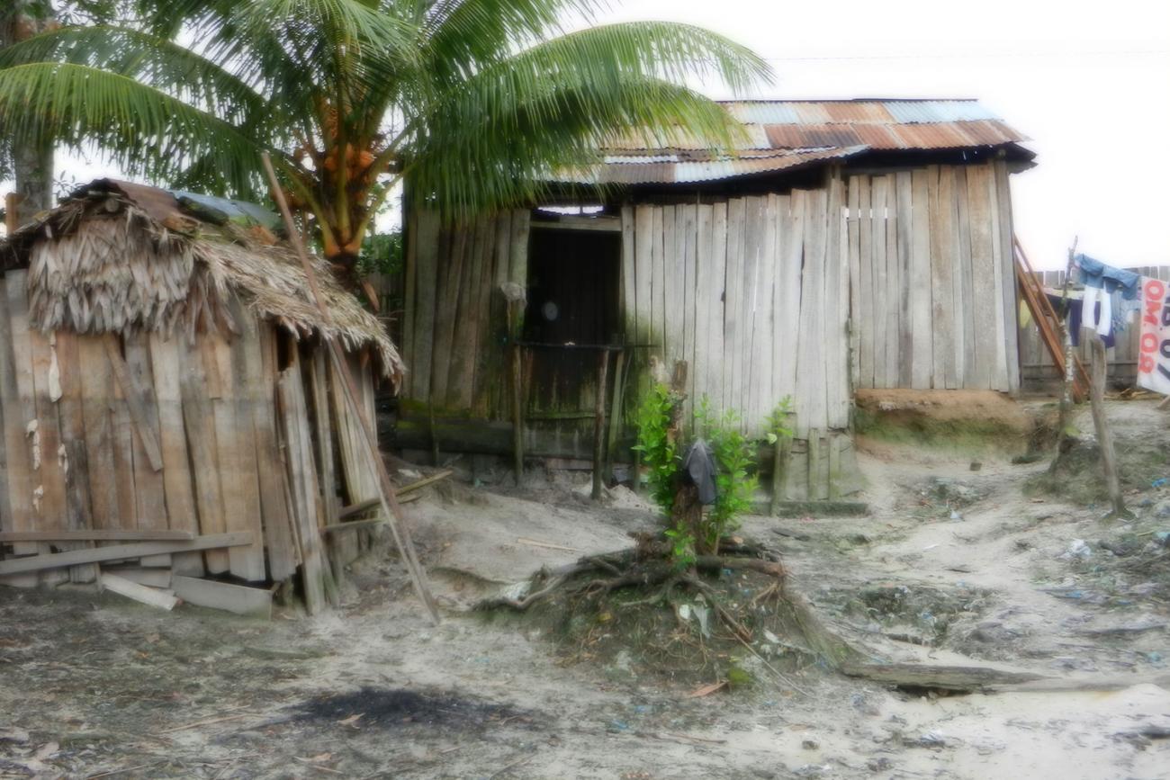 Picture shows weathered, rain-beaten buildings in the small Amazon Jungle community of Puerto Almendras, Peru