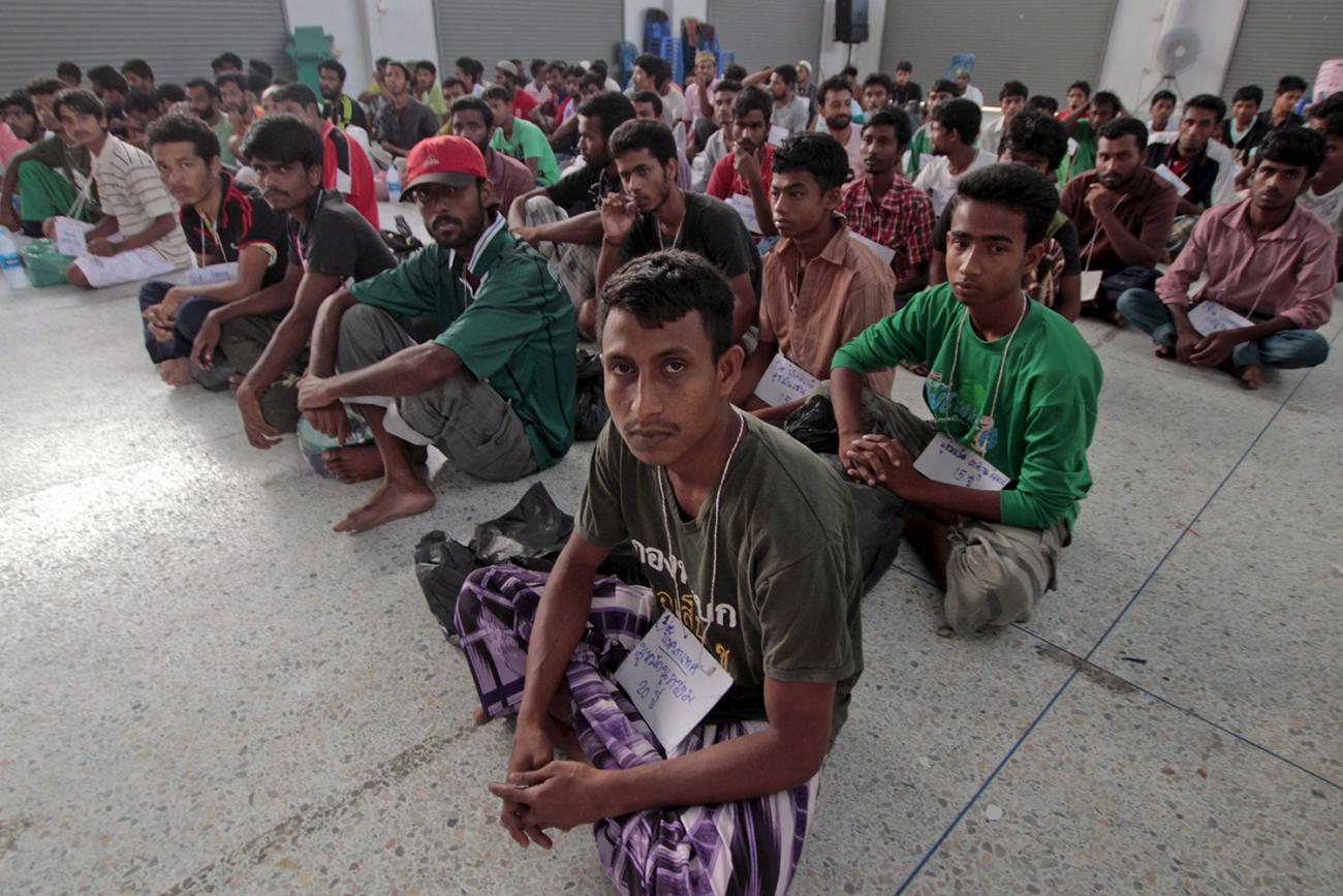 Migrants from Myanmar and Bangladesh in Thailand's southern Songkhla province on May 9, 2015. In 2001 Thailand launched a health insurance scheme for migrants and expanded it to dependents in 2005. Picture shows a triangle of men sitting cross-legged looking at the camera. REUTERS/Surapan Boonthanom.