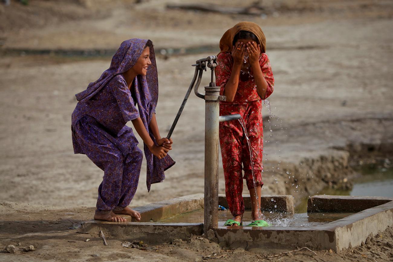 A hand pump provides access to water in the village of Lal Bux Lund in Pakistan's Sindh province on July 8, 2011, but 1 in 4 health facilities around the world lack basic water services. The picture shows two girls, one pumping, the other washing, and both laughing. REUTERS/Akhtar Soomro 