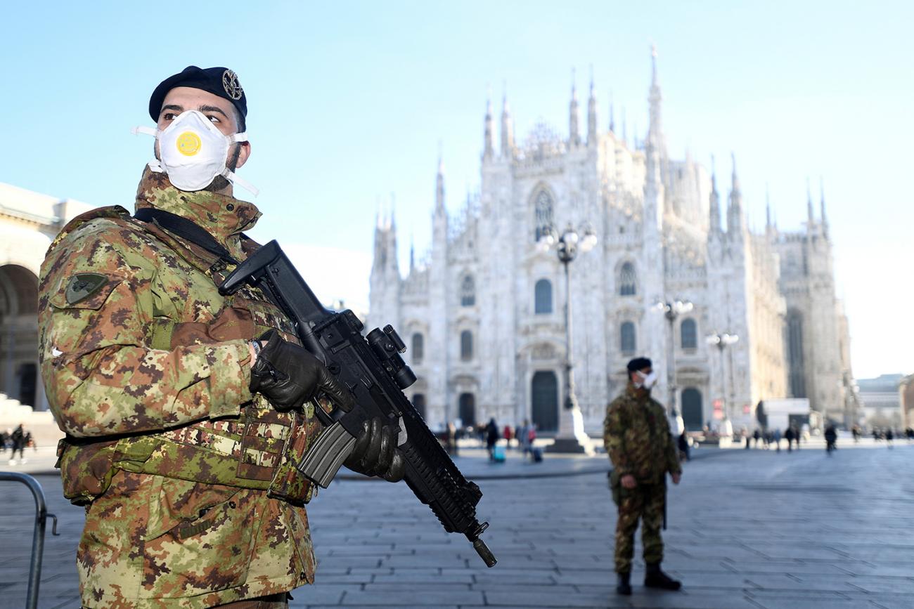 Military officers wearing face masks stand outside Duomo cathedral in Milan, Italy on February 24, 2020. The cathedral was closed by authorities due to the coronavirus outbreak. The photo shows a soldier in full combat gear wearing a mask and holding a military-style assault rifle. In the distance is the iconic architectural tourist destination. REUTERS/Flavio Lo Scalzo