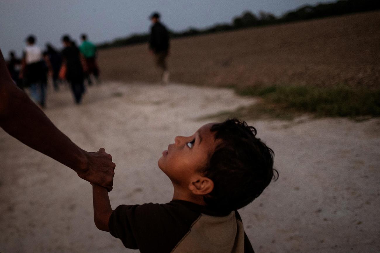A 3-year-old boy named Eduardo holding father Luis’s hand on Nov. 7, 2018. Both are from Central America, where progress toward reducing stunting in children under 5 has been particularly noticeable. Picture shows Eduardo looking up pensively at his father at they walk along a road in what appears to be dusk or pre-dawn dim light. Luis is off-camera and only his arm visible. REUTERS/Adrees Latif