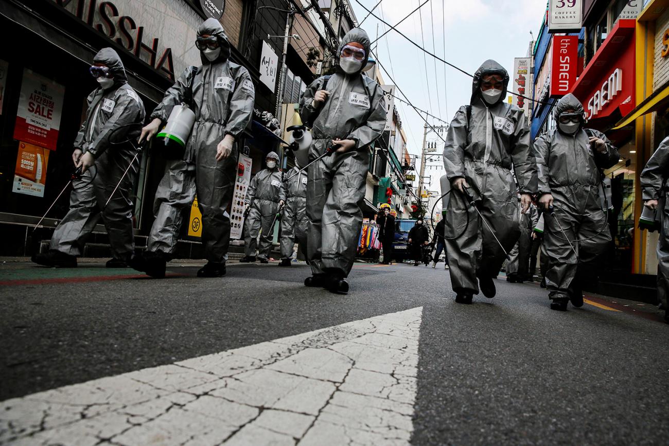 South Korean soldiers in protective gear sanitize a shopping street in Seoul, South Korea on March 4, 2020. The image is striking showing the soldiers dressed in silver space-suit looking protective gear walking down a more or less abandoned street in what appears to be a normally busy shopping district. REUTERS/Heo Ran
