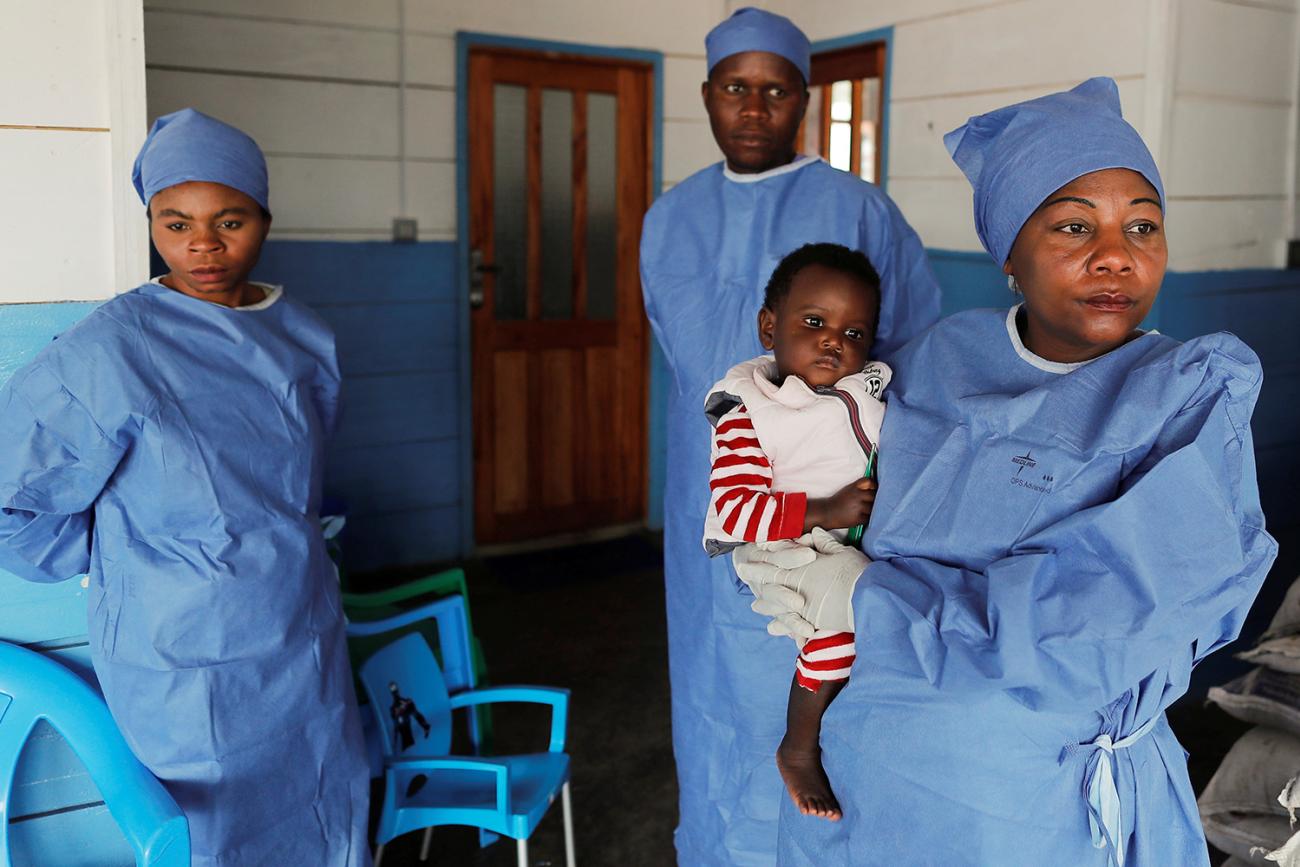 Arlette Kavugho, 40, a mother of six who survived an Ebola infection stands in Katwa, Democratic Republic of Congo, on October 2, 2019 holding 16 months old Kambale Eloge, whose mother died of Ebola. Photo shows Arlette holding the baby in front of a clinic while two other health workers stand in the background. REUTERS/Zohra Bensemra