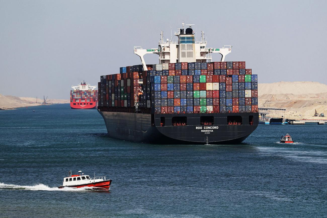 Container ship RDO Concord sails through the Suez Canal on November 17, 2019. The picture places the viewer in the wake of a massive freighter stacked high with metal shipping containers as a smaller patrol-type boat passes in the foreground. REUTERS/Mohamed Abd El Ghany