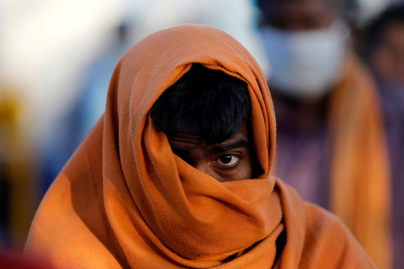 A homeless man stands in a queue as he waits for food during a 21-day nationwide lockdown to slow the spreading of the coronavirus disease (COVID-19) in New Delhi, India on April 3, 2020. The image is very striking showing the man with a large wrap around his head and mouth against a creamy, out of focus, colorful background. REUTERS/Adnan Abidi 