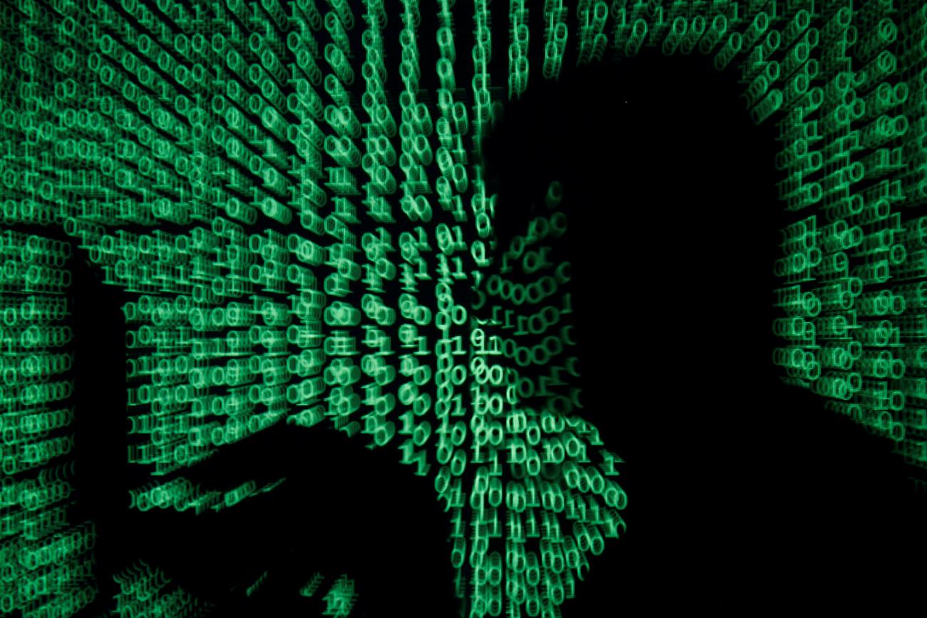 We are facing a digital moment of truth as a result of the new coronavirus. A man holds a laptop computer as cyber code is projected on him in this illustration and picture produced on May 13, 2017. the image shows the silhouette of a man on a laptop with green ones and zeroes, reminiscent of the film "The Matrix" projected over the image. REUTERS/Kacper Pempel/Illustration