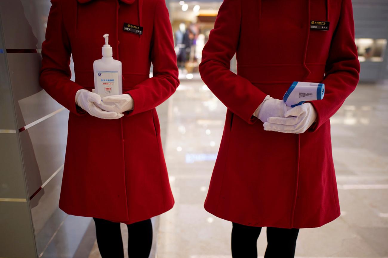 This is a striking photo of the torsos, waists and thighs of two women wearing brilliant red dresses standing at attention. 