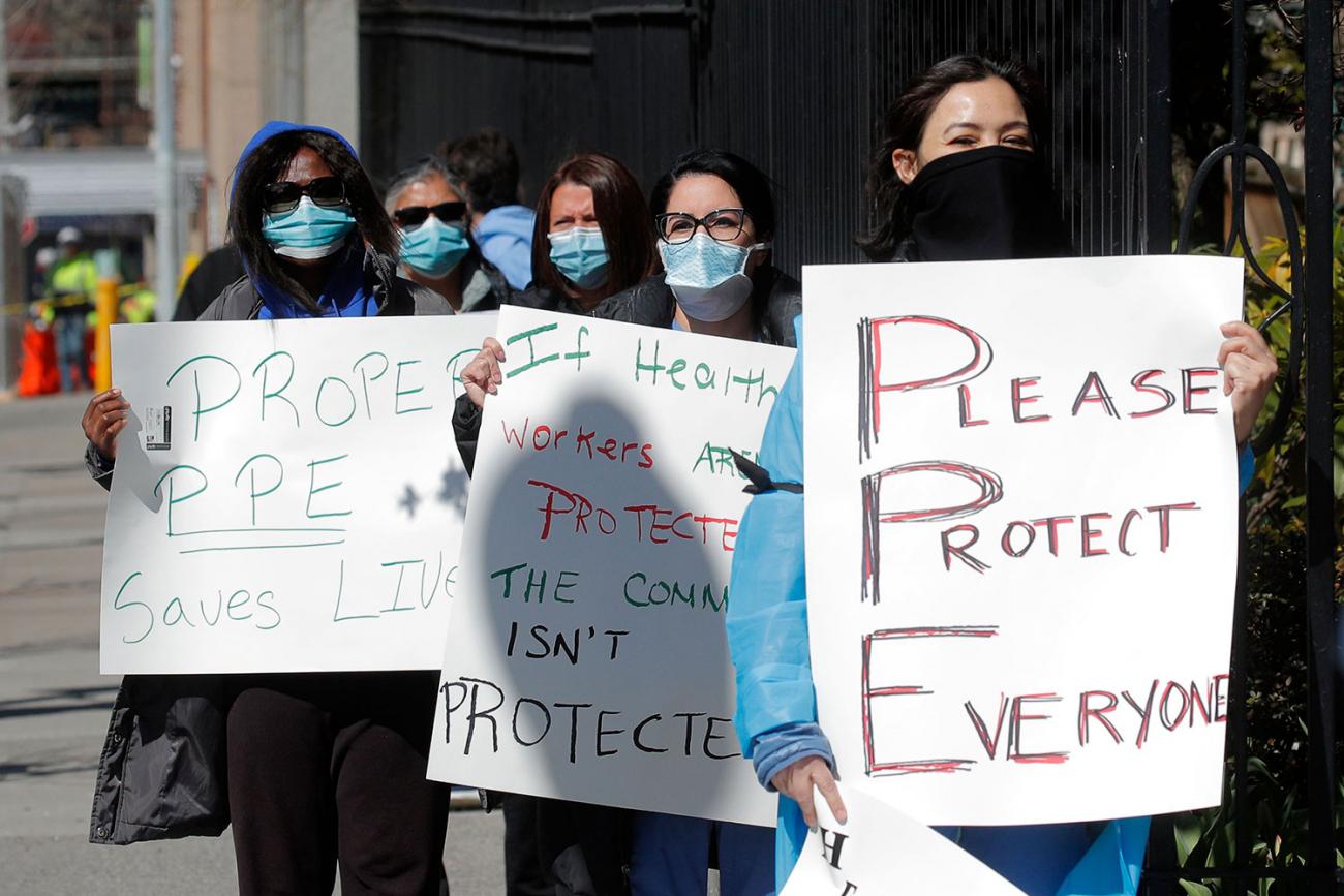 Nurses at Montefiore Medical Center in New York City's Bronx borough hold a protest demanding N95 masks and other critical personal protective equipment during the COVID-19 pandemic on April 2, 2020. The photo shows a number of nurses lined up holding placards. One of them plays off the term PPE and spells out "Please Protect Everyone." REUTERS/Brendan Mcdermid