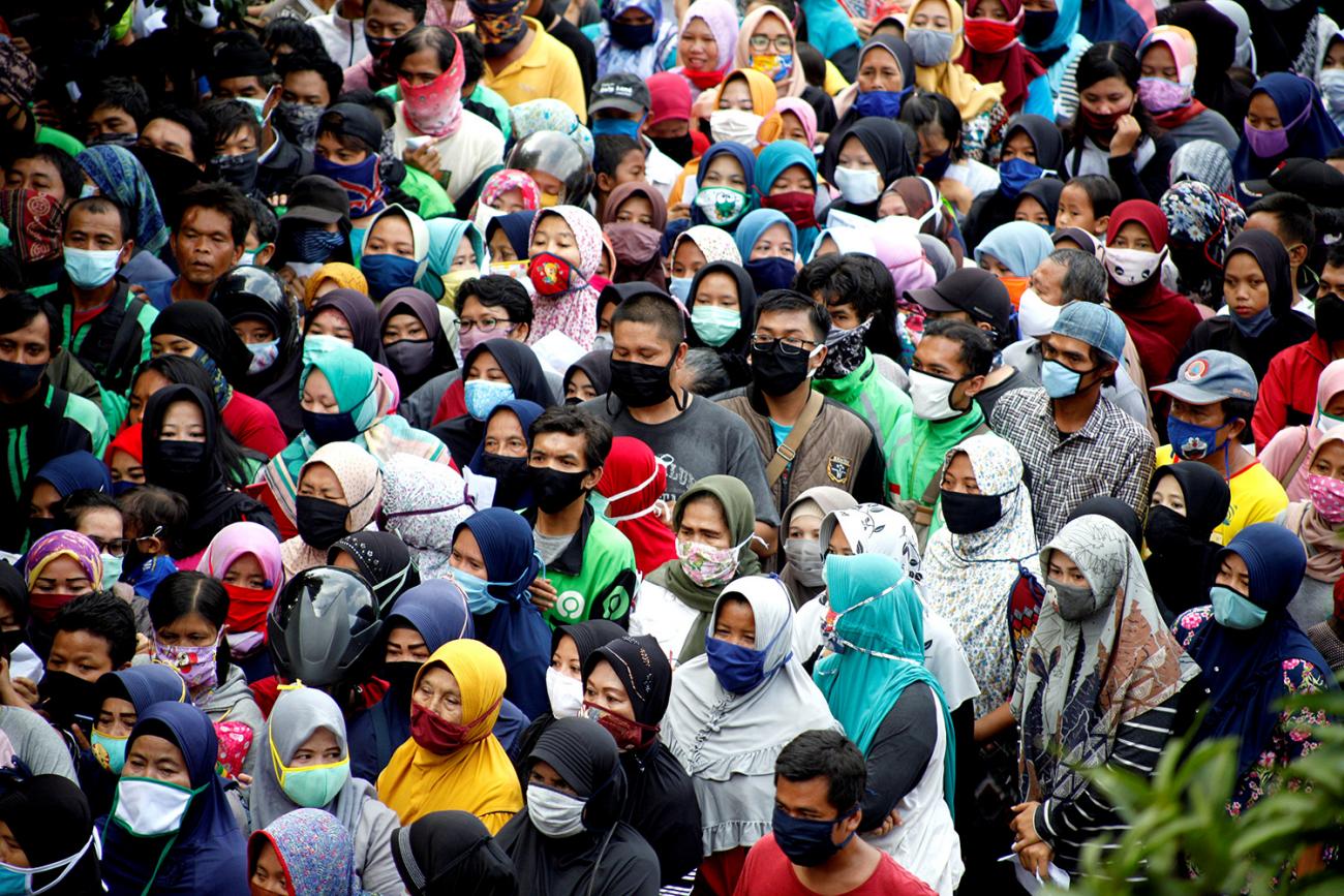 Indonesians queue to get free food without social distancing amid the coronavirus disease (COVID-19) outbreak in Bogor, Indonesia, on April 20, 2020. The photo shows a crush of people, many of them wearing face masks, crowded in all parts of the shot's frame. REUTERS/Antara Foto/Yulius Satria Wijaya