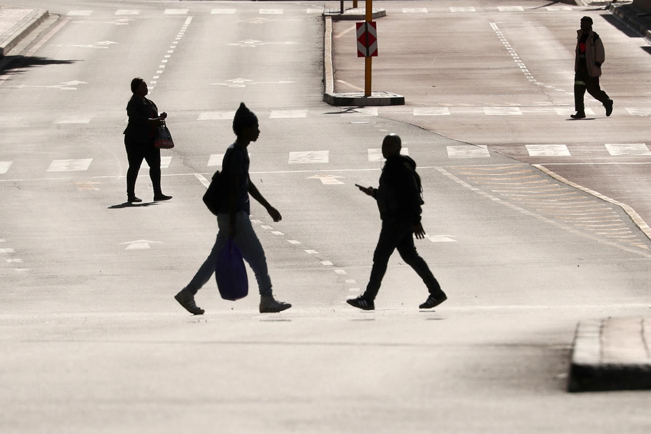 People cross normally busy—now largely empty—Adderley Street in central Cape Town, South Africa, on April 14, 2020, during the 21-day nationwide lockdown aimed at limiting the spread of coronavirus. This is a stunning photo showing a broad main thoroughfare that is completely bereft of cars. Four people are seen crossing the wide street, each silhouetted against the early or late sun reflecting off the asphalt pavement. REUTERS/Mike Hutchings