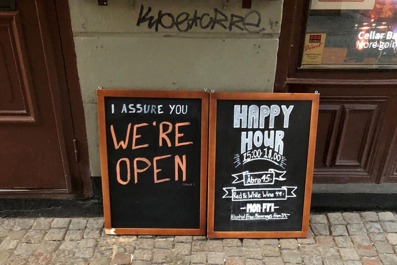 In a country that didn't lockdown during the coronavirus pandemic, a sign assures people that the bar is open during the COVID-19 outbreak—outside a pub in Stockholm, Sweden, on March 26, 2020. Picture Shows two side-by-side chalk placards in front of a restaurant advertising a happy hour inside. One of the signs reads, "I assure you WE'RE OPEN." REUTERS/Colm Fulton