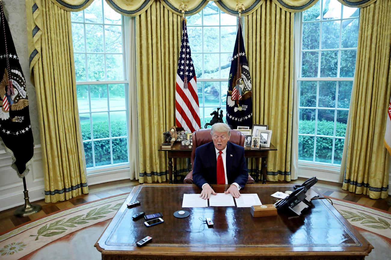 U.S. President Donald Trump looks at his briefing papers as he answers questions during an interview with Reuters about China, the coronavirus pandemic and other subjects on April 29, 2020. The photo shows the president at his desk in the Oval Office. REUTERS/Carlos Barria
