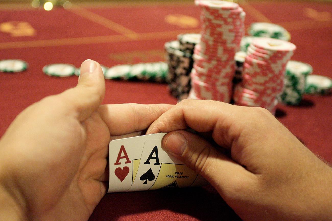 A player checks his cards during the finals of the Russian Masters Poker Cup at the Azov-City, Russia, gambling zone, south of Russia's southern city of Rostov-on-Don, on September 23, 2010. Photo shows a pair of hands holding up the corners of two cards to reveal a pair of aces. A large stack of chips is in the background. REUTERS/Vladimir Konstantinov 