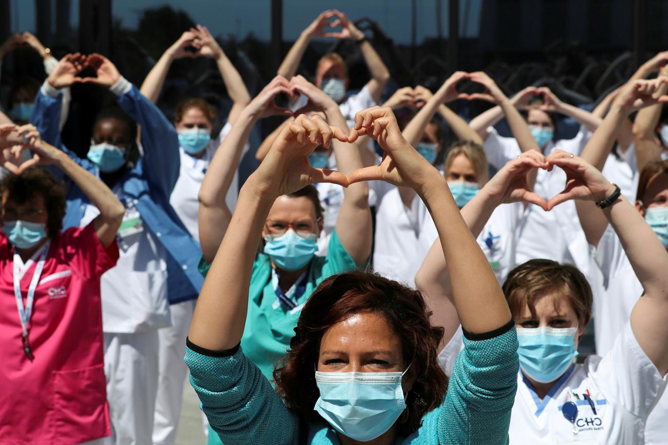 Health-care workers, nurses, and doctors, protesting under the movement called "Take Care of Care" during the coronavirus crisis, at the MontLegia CHC Hospital in Liege, Belgium, on May 15, 2020. The photo shows a large number of health workers standing together and holding up a heart symbol above their heads. REUTERS/Yves Herman