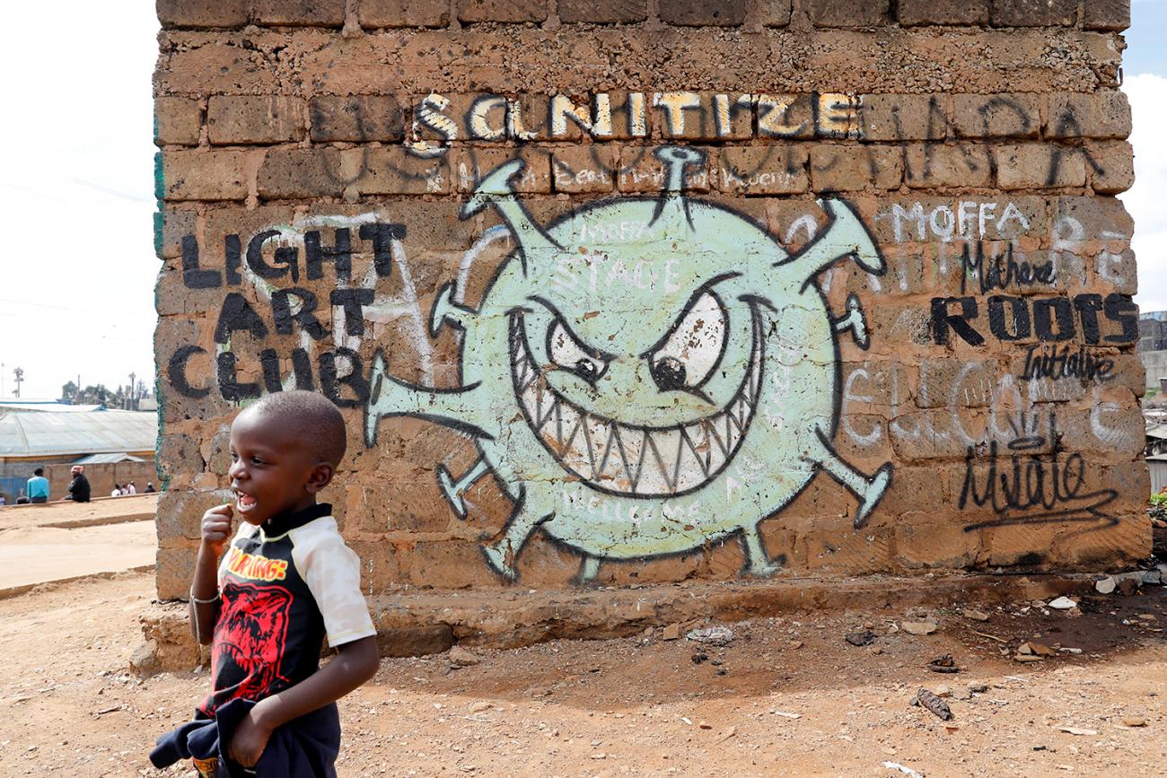 A boy stand in front of a graffiti promoting the fight against the coronavirus disease (COVID-19) in the Mathare slums of Nairobi, Kenya, on May 22, 2020. This is a powerful photo of a young boy walking in front of a sinister depiction of the virus with a face that appears to be sneeringly looking at the boy. REUTERS/Baz Ratner