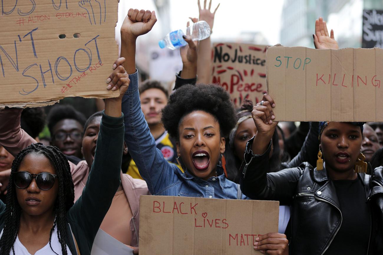 Demonstrators from the Black Lives Matter movement march through central London on July 10, 2016, during a demonstration against the killing of black men by police in the United States. The photo shows a huge crowd with people facing the camera with homemade signs, fists raised, and shouting slogans. AFP/Daniel Leal-Olivas via Getty Images