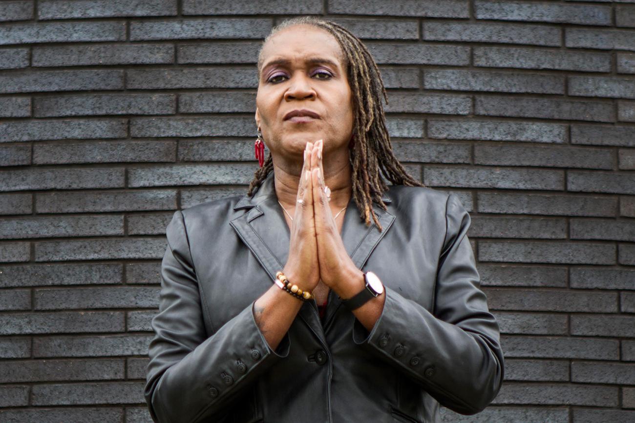 Minneapolis City Council Vice President Andrea Jenkins, who gave this interview. The photo shows the council vice president standing in front of a slate-colored brick wall with her hands together looking at the camera. IMAGE from Brooke Ross Photography