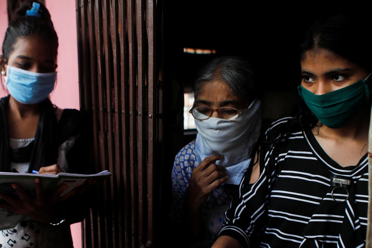 Community health volunteers check the pulse of a resident during a check-up campaign for COVID-19 in Mumbai, India.