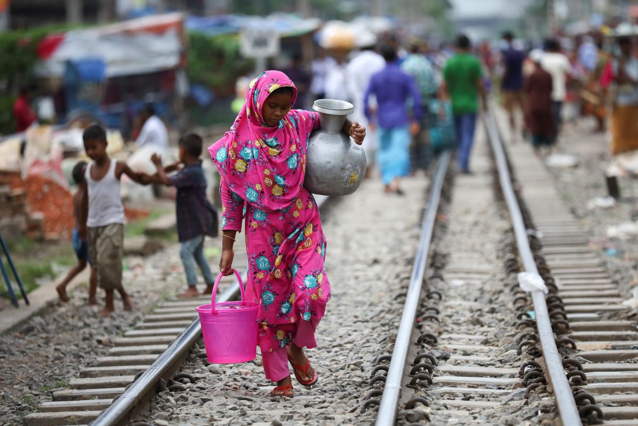 A slum dweller woman carries drinking water in Dhaka, Bangladesh, September 15, 2020. REUTERS/Mohammad Ponir Hossain