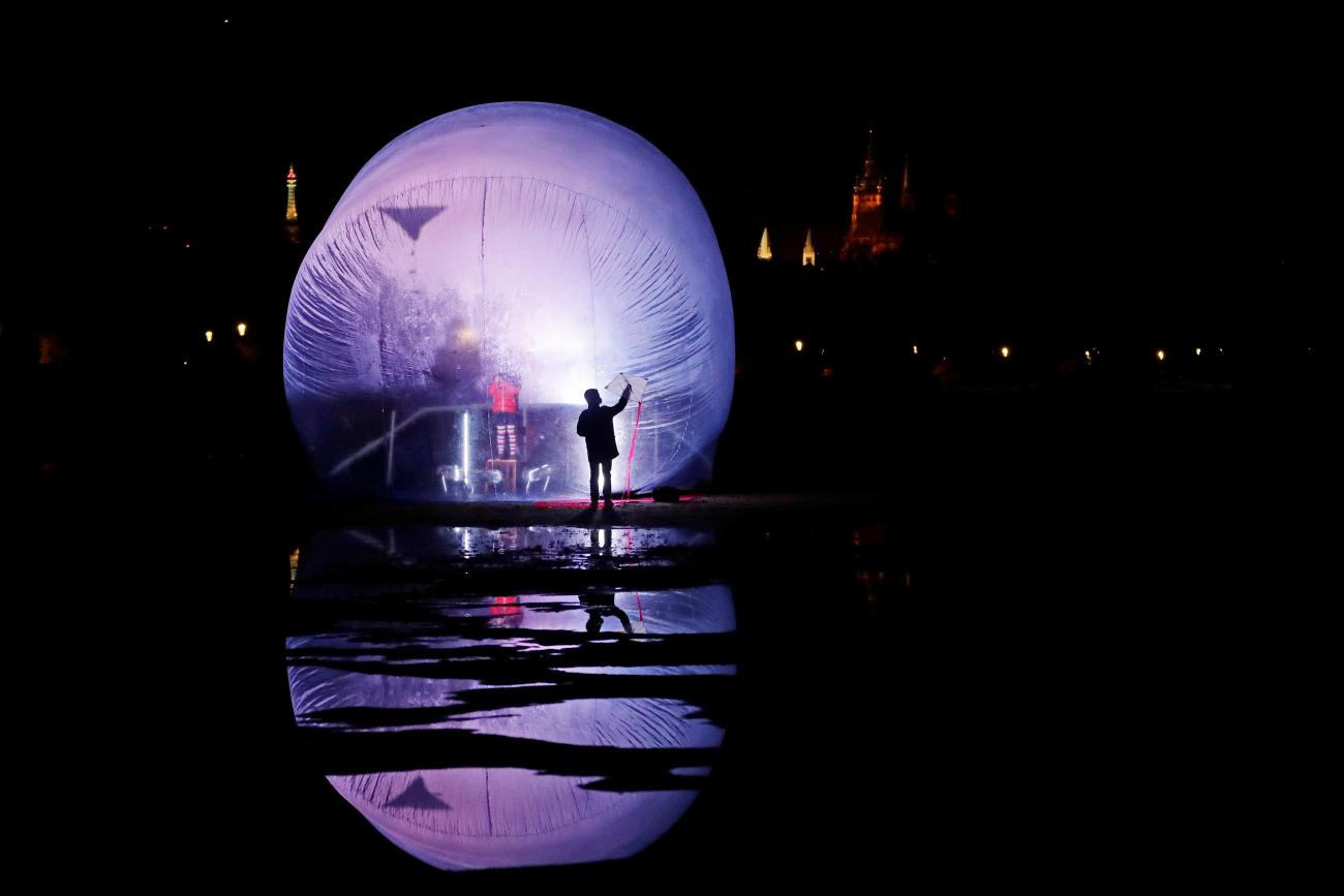 A child flies a kite inside a giant inflatable plastic bubble during a performance of the artistic group Cirk La Putyka called "Isolation" in a park, as the spread of the coronavirus disease (COVID-19) continues in Prague, Czech Republic