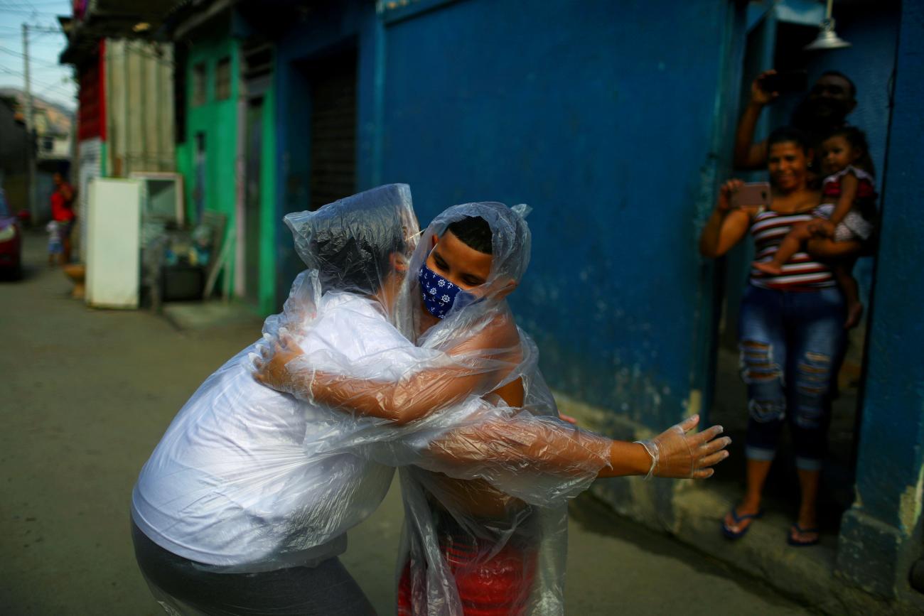 Teacher Maura Silva, who works for public school Escola Municipal Frei Vicente de Salvador and who created a "hug kit" using plastic covers, embraces her student Yuri Araujo Silva at Yuri's home, amid the coronavirus disease (COVID-19) outbreak, in the 77 Padre Miguel slum in Rio de Janeiro, Brazil July 23, 2020.