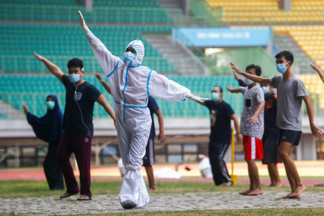 A health worker wearing protective suit and patients exercise at the Patriot Chandrabhaga Stadium which has been converted into a quarantine house amid the coronavirus disease (COVID-19) outbreak, in Bekasi, on the outskirts of Jakarta, Indonesia
