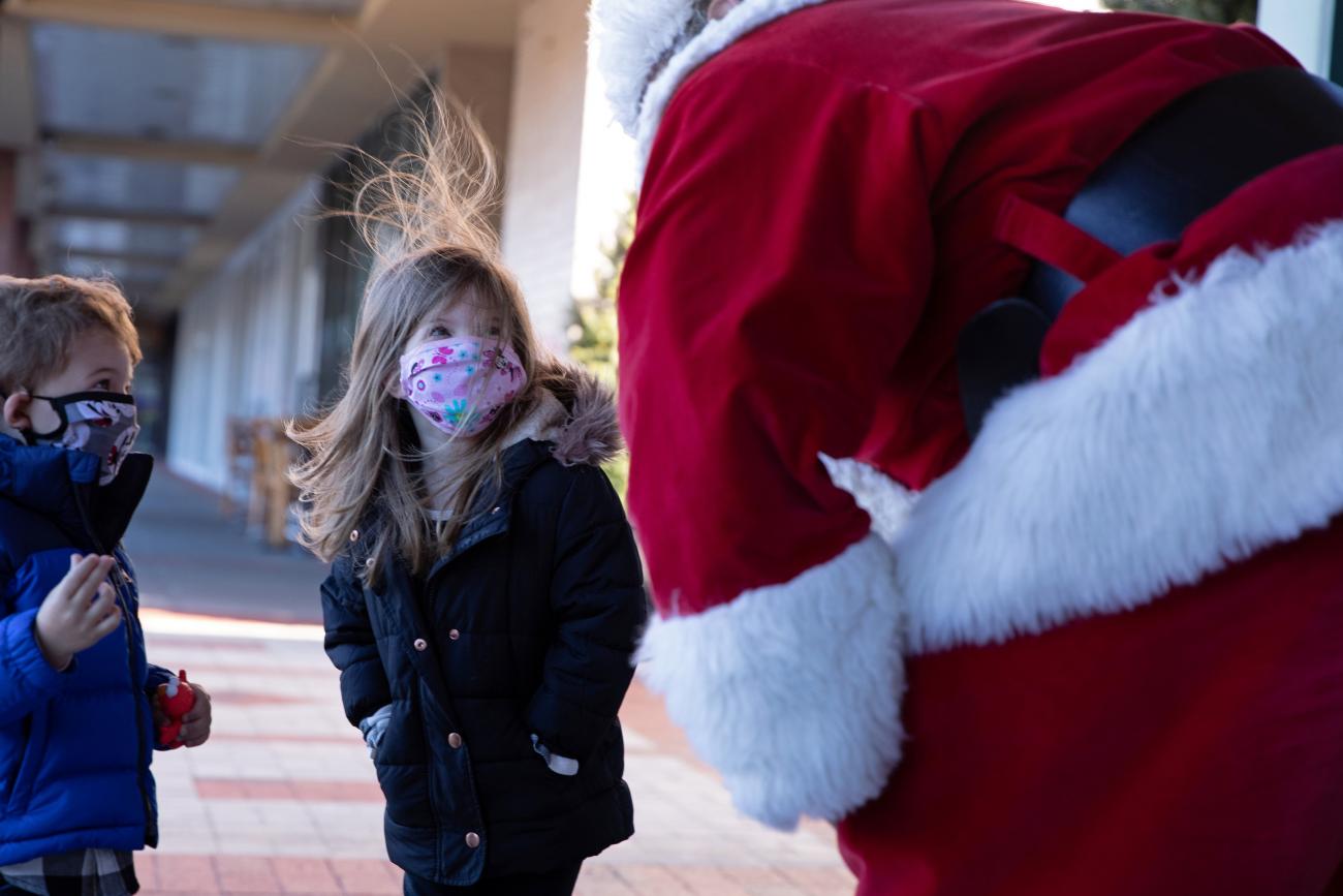 Santa Claus greets a young girl outside, both wearing masks as a precautionary measure in Queens as the global outbreak of the coronavirus disease continues in New York City on December 6, 2020.