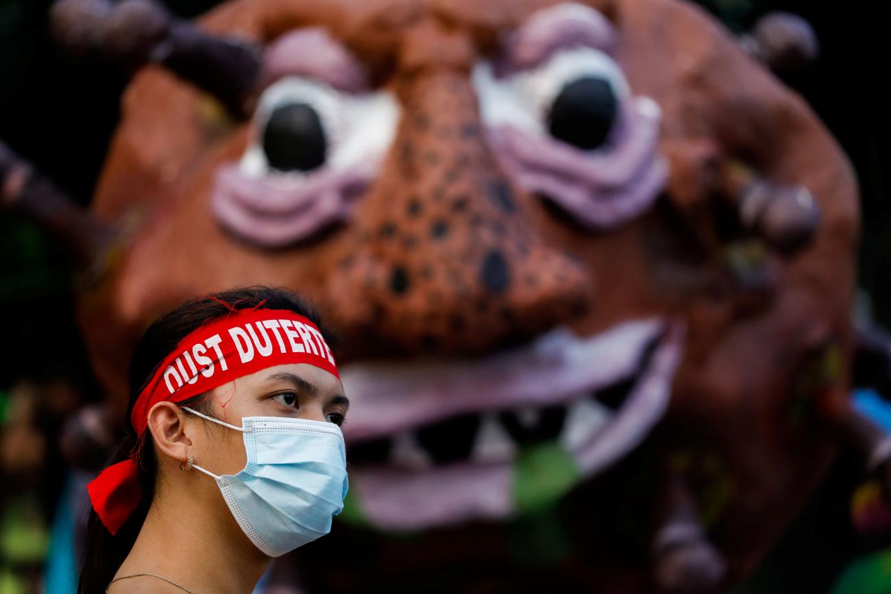 An activist wearing a statement band that writes "Oust Duterte" is photographed in front of an effigy dubbed "Duterte Virus" during a protest in Manila, Philippines on September 21, 2020.