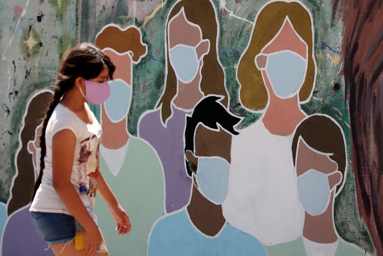 A girl wearing a face mask to prevent the spread of the coronavirus disease (COVID-19) walks past a graffiti in homage to the medical staff, at the San Martin hospital, in La Plata, on the outskirts of Buenos Aires, Argentina January 21, 2021.