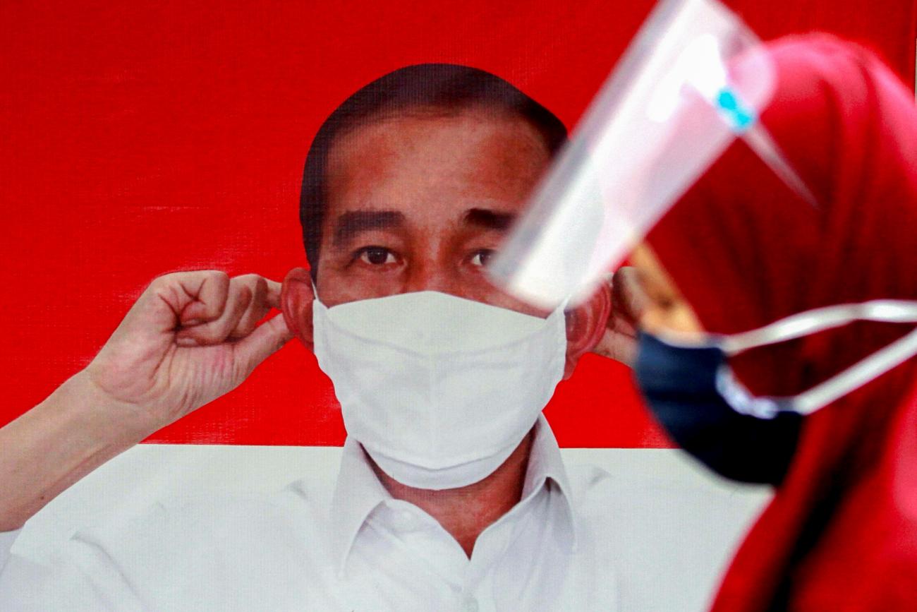 A woman walks past a banner depicting Indonesian President Joko Widodo promoting awareness of the coronavirus disease in Jakarta, Indonesia on September 28, 2020.