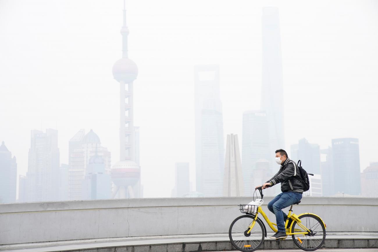 A man wearing a face mask rides a bicycle on a bridge in front of the financial district of Pudong covered in smog during a polluted day in Shanghai, China on November 22, 2017.