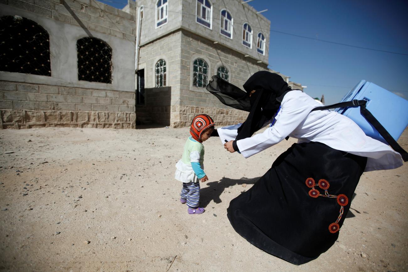 A health worker holds a girl to give her polio vaccination drops during a house-to-house anti-polio vaccination campaign in Yemen's capital Sanaa, April 12, 2016.